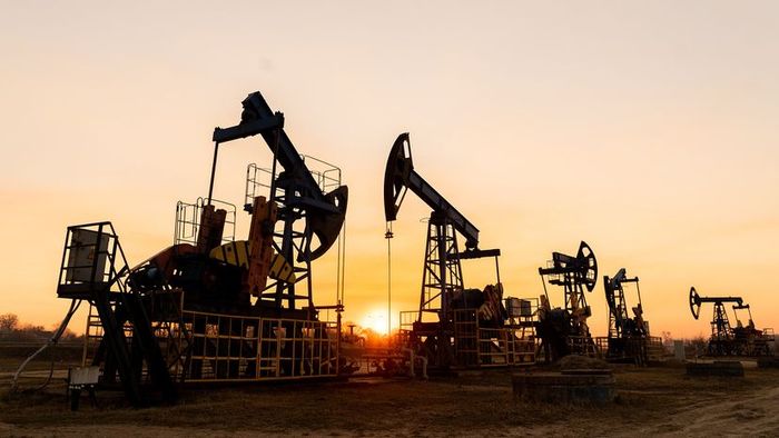 A striking image of oil rigs silhouetted against a stunning sunset, with the sun dipping between them.