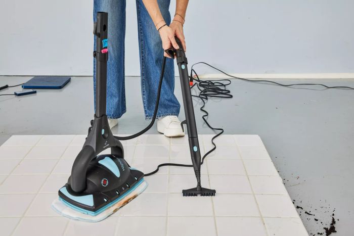 A person cleaning grout on a tile floor with the Euroflex Vapour Pro M4S