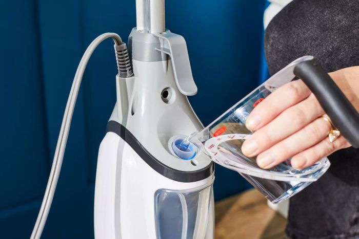 A person pouring water into the canister of the Shark S3601 Professional Steam Pocket Mop