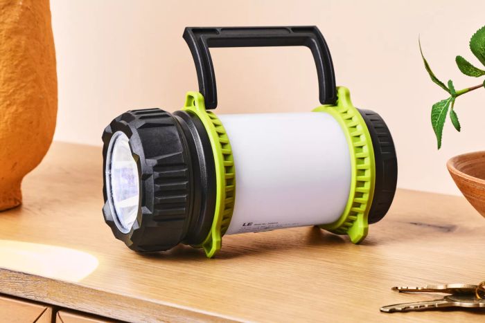 The Lighting Ever 3300019 Rechargeable LED Camping Lantern shining brightly on a wooden surface.