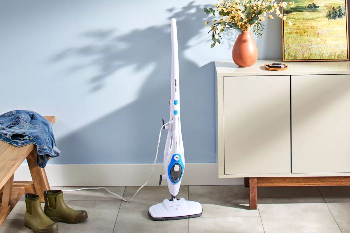 A PurSteam 10-in-1 Steam Mop positioned beside a cabinet on tiled flooring