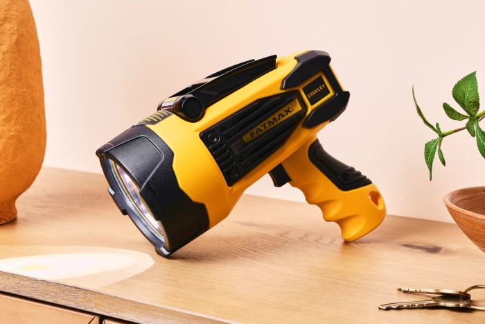 A lit Stanley Fatmax Rechargeable Lithium Ion LED Spotlight Flashlight placed on a wooden counter.