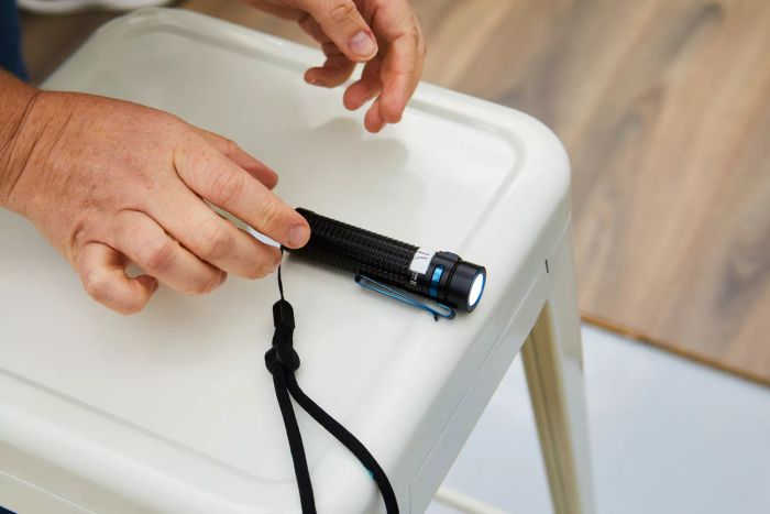 A person holding the Olight S2R Baton II USB Magnetic Rechargeable Flashlight at an angle.