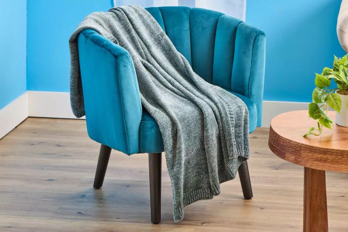 A luxurious sage-colored West Elm chenille throw elegantly draped over a fabric chair