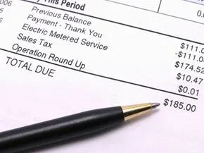 A piece of paper displaying an electric bill with a pen resting on top.