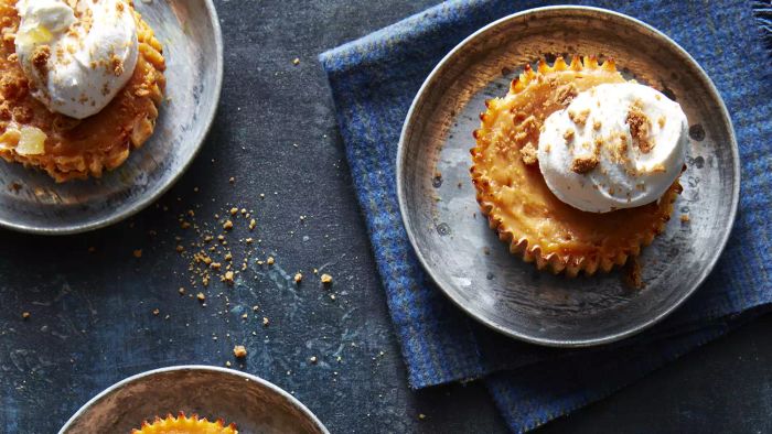 Mini pumpkin pies, crowned with whipped cream, set against a striking blue backdrop.