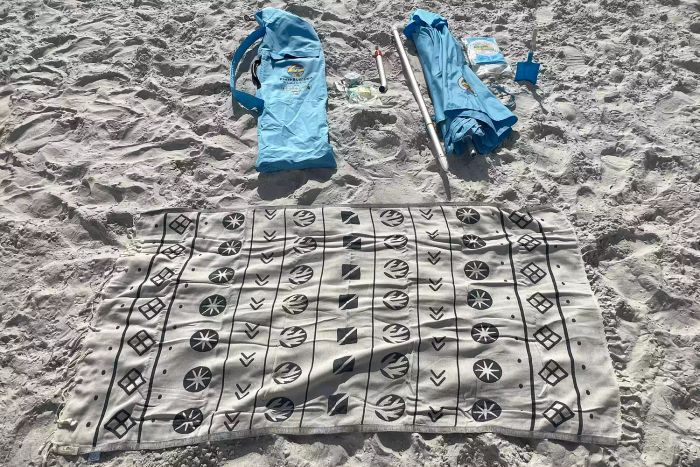 The beachBUB All-In-One Beach Umbrella System components spread out on the sand