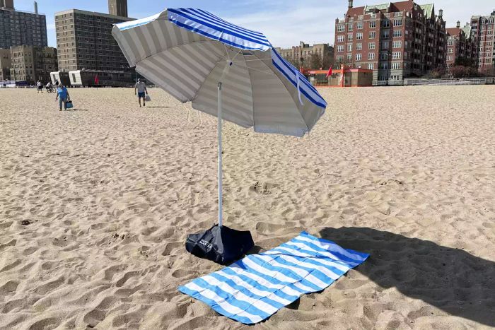 OutdoorMaster Beach Umbrella with Sand Bag and Cup Holder fully set up on the beach
