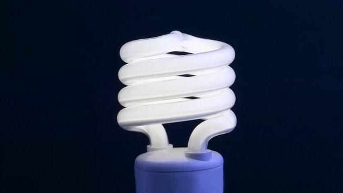 A glowing spiral CFL bulb set against a dark backdrop