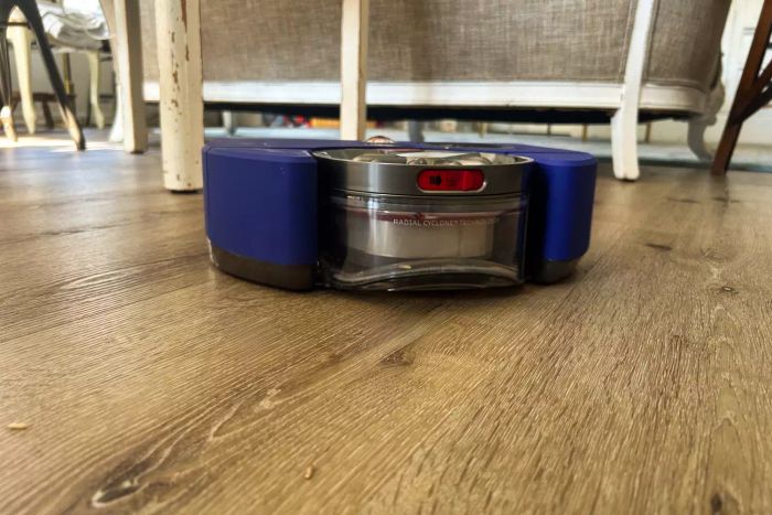 A close-up shot of the Dyson 360 Vis Nav Robot Vacuum resting on a wooden floor.