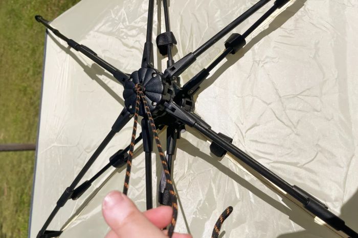 A close-up shot of a hand gripping a rope attached to the top of the Oileus XL Beach Tent