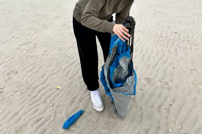 A person assembling the Pacific Breeze Easy Setup Beach Tent on the beach
