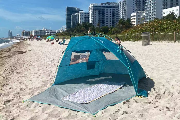 The Lightspeed Outdoors Quick Cabana Beach Tent showcased on the sand with a towel inside, ready to provide shelter from the sun.