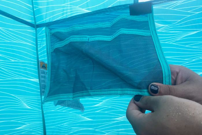 A close-up shot of hands gripping the pocket of the Lightspeed Outdoors Quick Cabana Beach Tent.