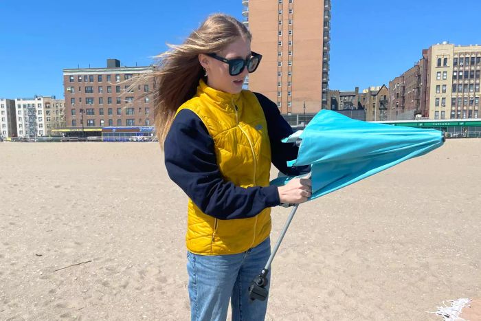 A person unfolding the Sport-Brella Versa-Brella SPF 50+ Adjustable Umbrella.