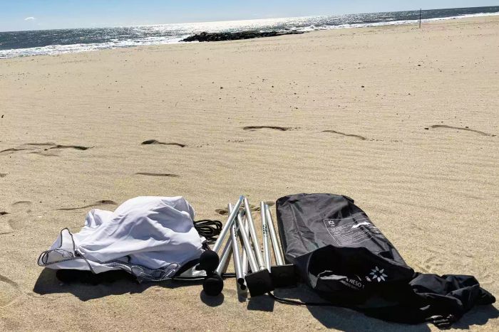 Various components of the Neso 1 Beach Tent spread out on the sand.