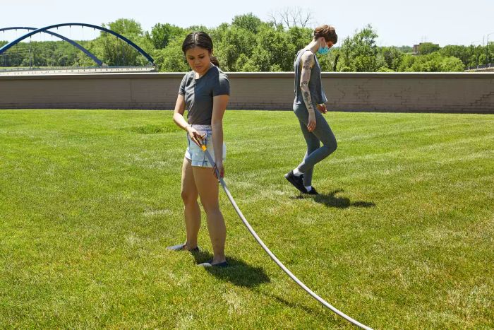 A person holding the Eley 5/8-Inch Polyurethane Garden Hose while testing it in a grassy area.