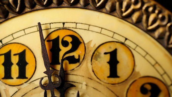 A close-up of a vintage clock nearing the stroke of midnight.