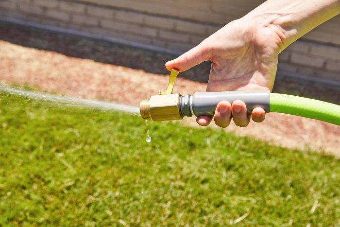 A hand gripping the Flexzilla Zillagreen Garden Hose as it sprays water