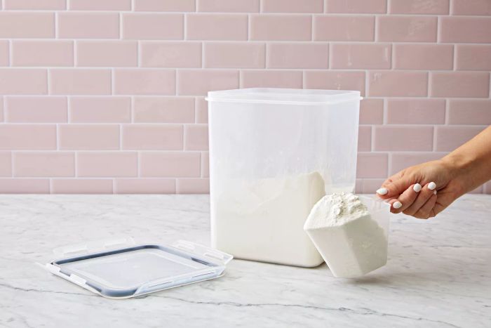 A hand removing flour from a Vtopmart Large Food Storage Container