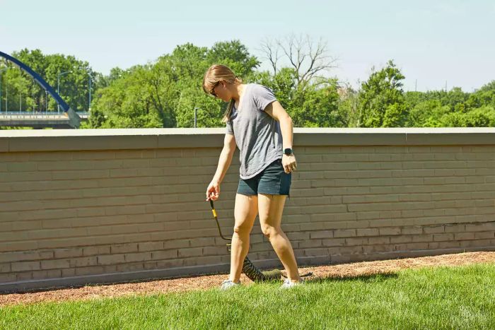 A woman pulling the Water Right Coil Garden Hose across a lawn