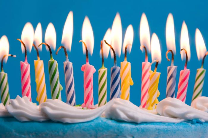 A close-up view of birthday candles on a cake with a blue backdrop, captured in shallow focus.