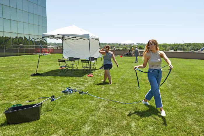 A person pulling the H2O Works Garden Flat Soaker Hose through grass.