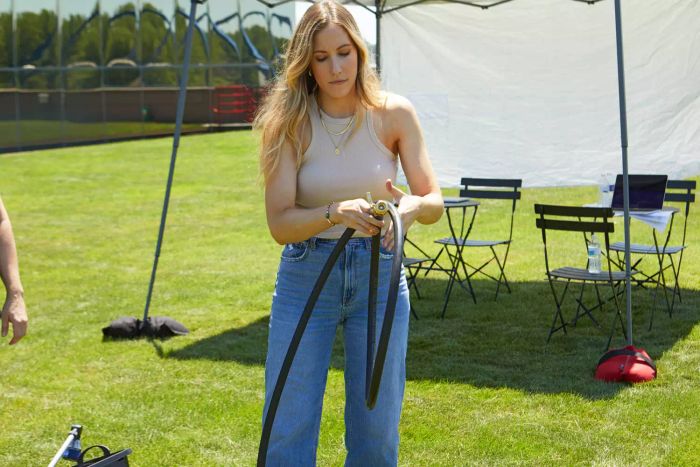 A person holding the Briggs and Stratton Heavy-Duty Rubber Garden Hose in a grassy field.