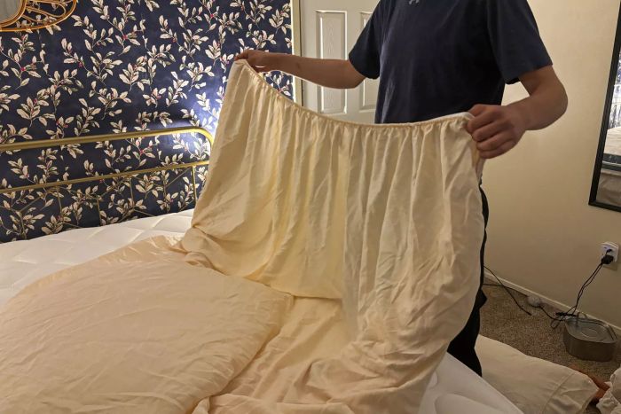 A person holds the fitted sheet from the Cosy House Collection Luxury Bed Sheets.