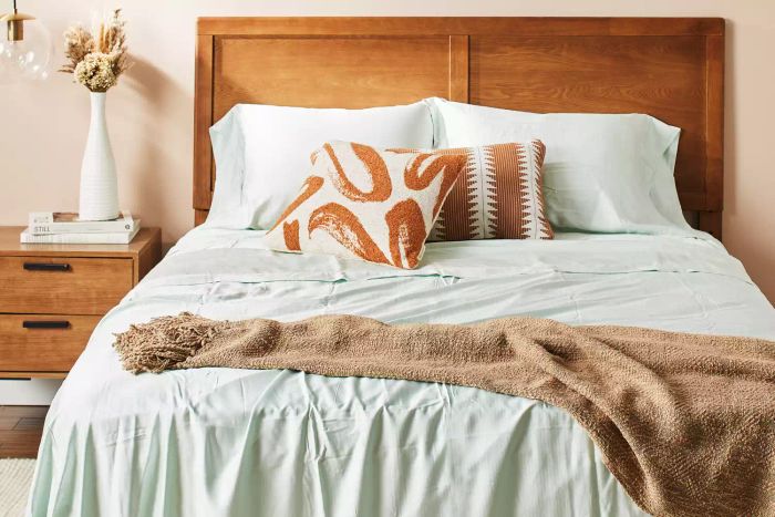 A bed made with the Bamboo Bliss Resort Bamboo Collection by RHH Bamboo Sateen Sheet Set, complemented by decorative pillows.