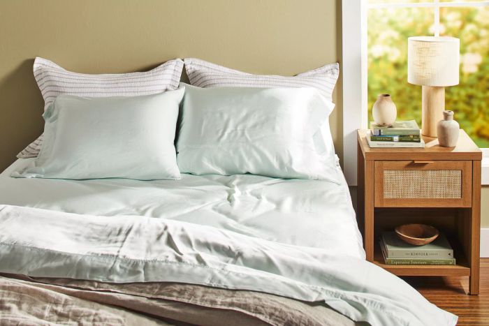 A bed set up with the Bamboo Bliss Resort Bamboo Collection by RHH Bamboo Sateen Sheet Set next to a nightstand.