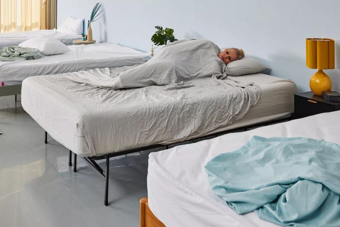 A person is covered by the Quince Linen Bamboo Sheet Set.