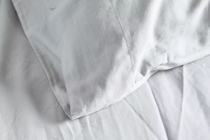 A close-up shot of the Quince Linen Bamboo Sheet Set laid out on a pillow and mattress.