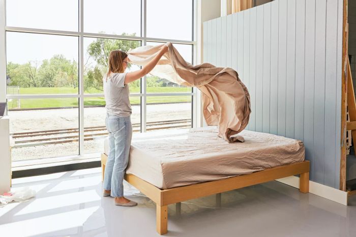 A person smoothing the top sheet of the Cozy Earth Bamboo Sheet Set over a mattress