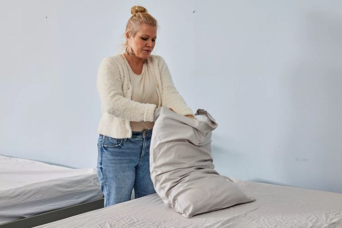 A person is seen placing a pillowcase from the Quince Linen Bamboo Sheet Set over a pillow.