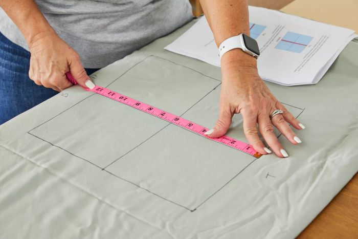 Person using a measuring tape to measure the Bamboo Bay 4-Piece Bamboo Sheet Set on a table.