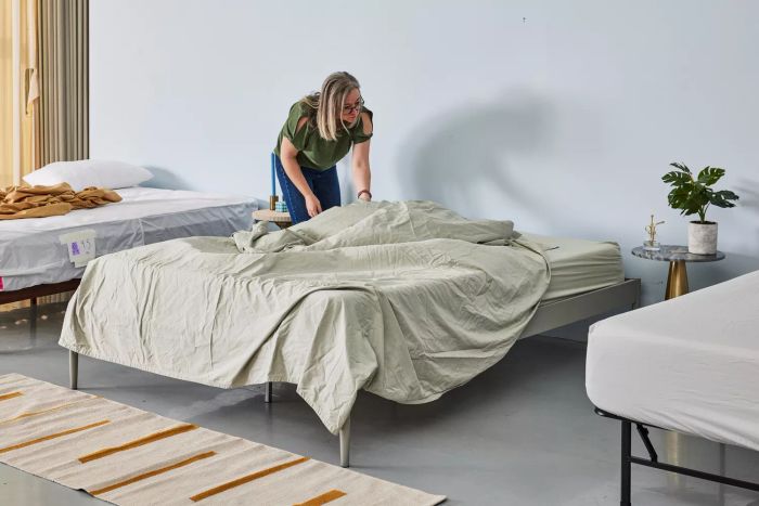 A person making the bed using the light green DreamFit DreamChill Collection Enhanced Bamboo Sheet Set.
