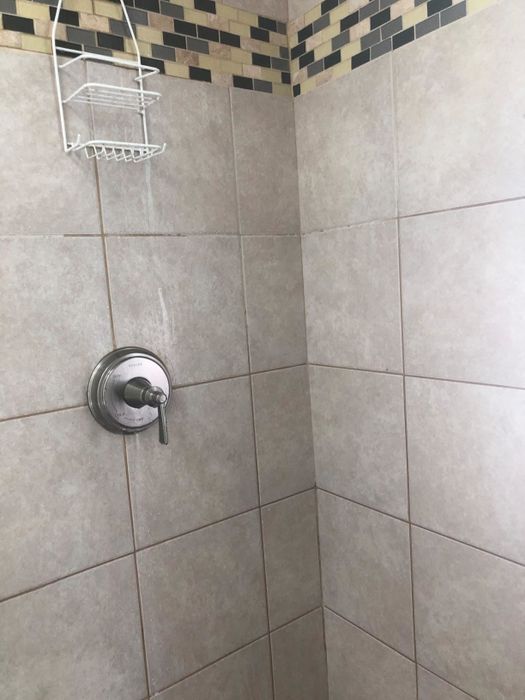 A reviewer's photo of the same shower now clean after using the mold and mildew spray
