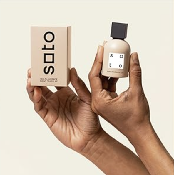 Two hands holding a bottle of touch-up paint along with its packaging