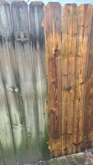 A wooden fence displaying the stark difference between freshly cleaned boards and those weathered with mildew, showcasing the transformative effects of pressure washing.