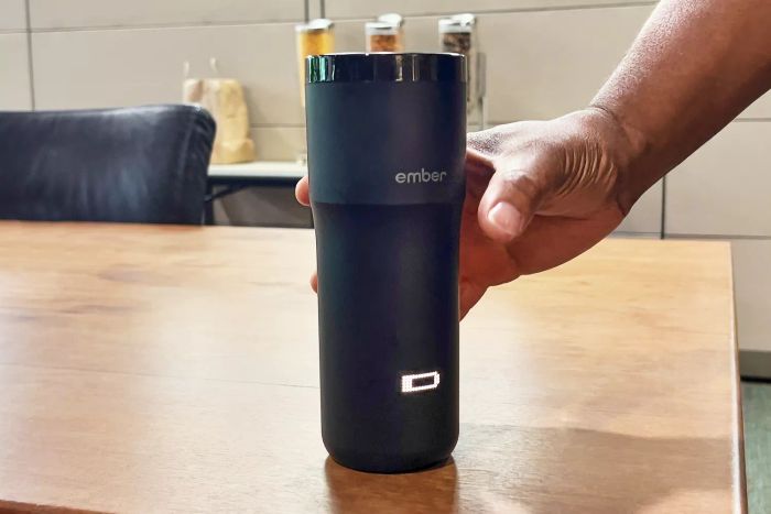 Hand placing the Ember Travel Mug 2 on a table