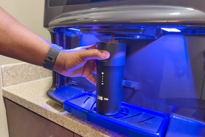 Hand holding the Ember Travel Mug 2 under a coffee machine as it fills