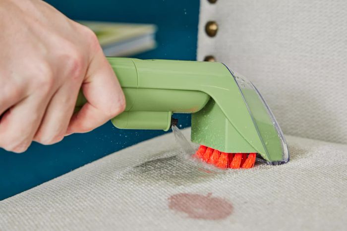 A close-up of the Bissell Little Green Portable Carpet Cleaner on a stain