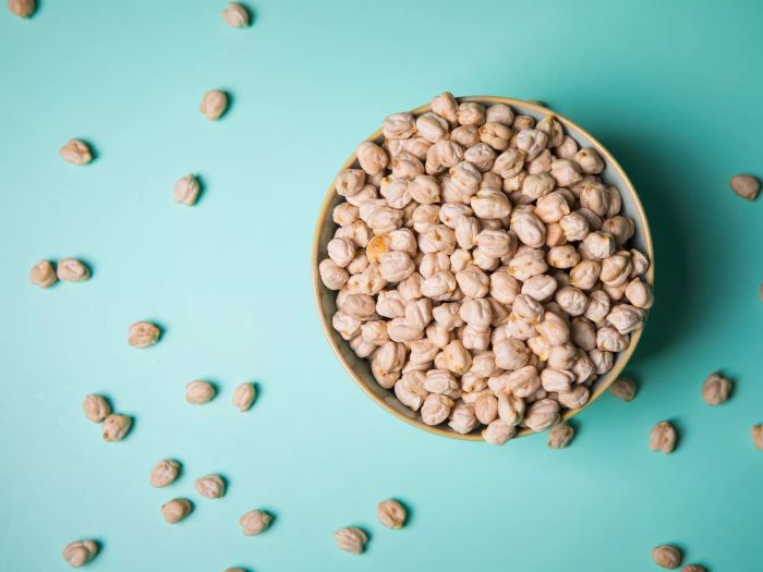 Aerial view of a bowl filled with chickpeas set against a teal-colored background