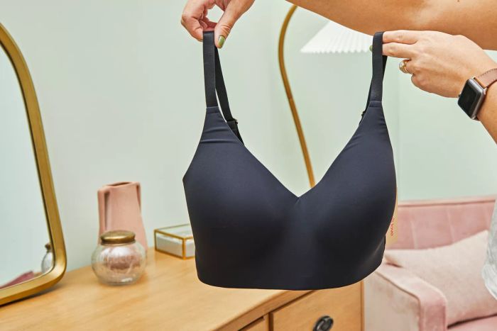 A person holds up the Thirdlove All Day Lace Wireless Bra by its straps