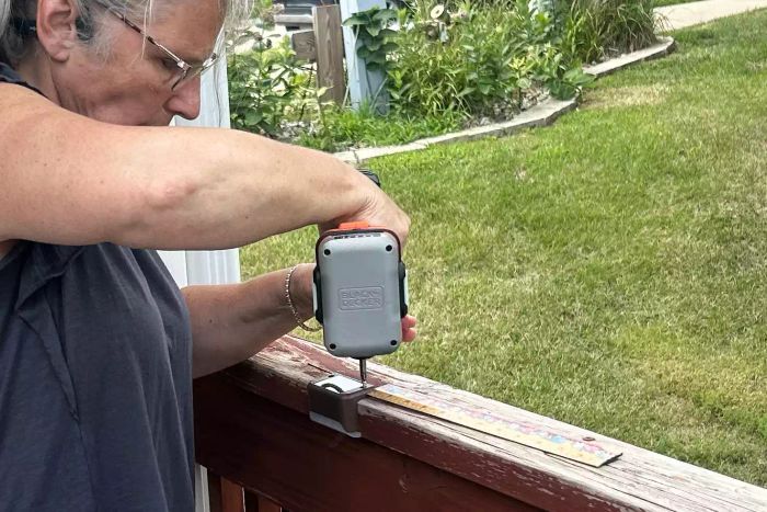 A person attaches the SOLPEX Solar Deck Lights to a deck railing