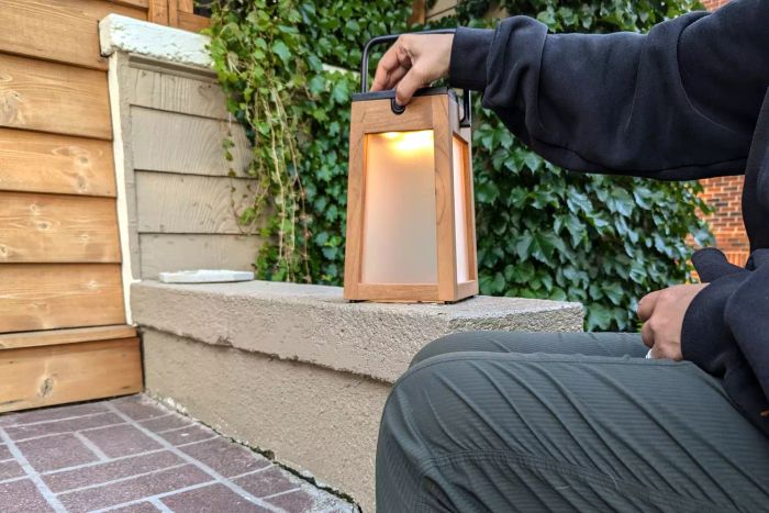 A person presses a button on the Pottery Barn Nellie Outdoor Lantern