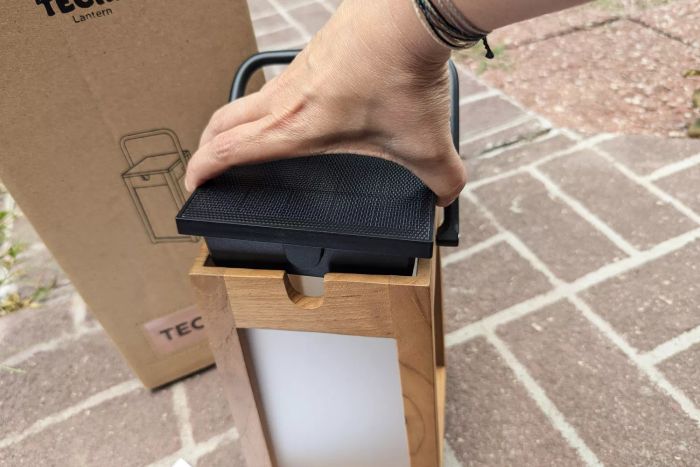 A person positions the solar panel atop the Pottery Barn Nellie Outdoor Lantern