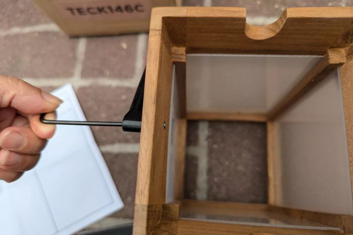 A person uses a screwdriver to put together the Pottery Barn Nellie Outdoor Lantern