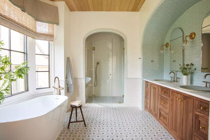 A bathroom featuring an arched shower entrance with wooden cabinetry.